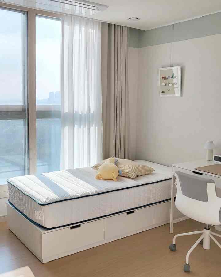Bright and simple kids' room with white and natural tones, featuring a mattress bed and a desk by the window