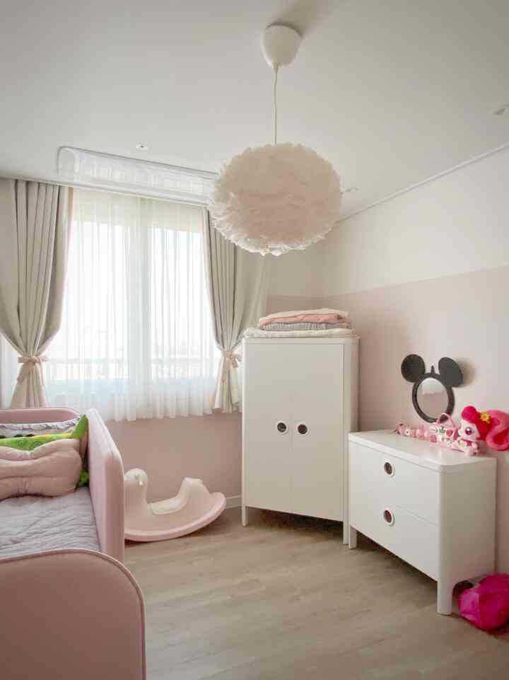 ピンクとホワイトの色調の子供部屋、ベッドやワードローブなどが配置された雰囲気のあるインテリア