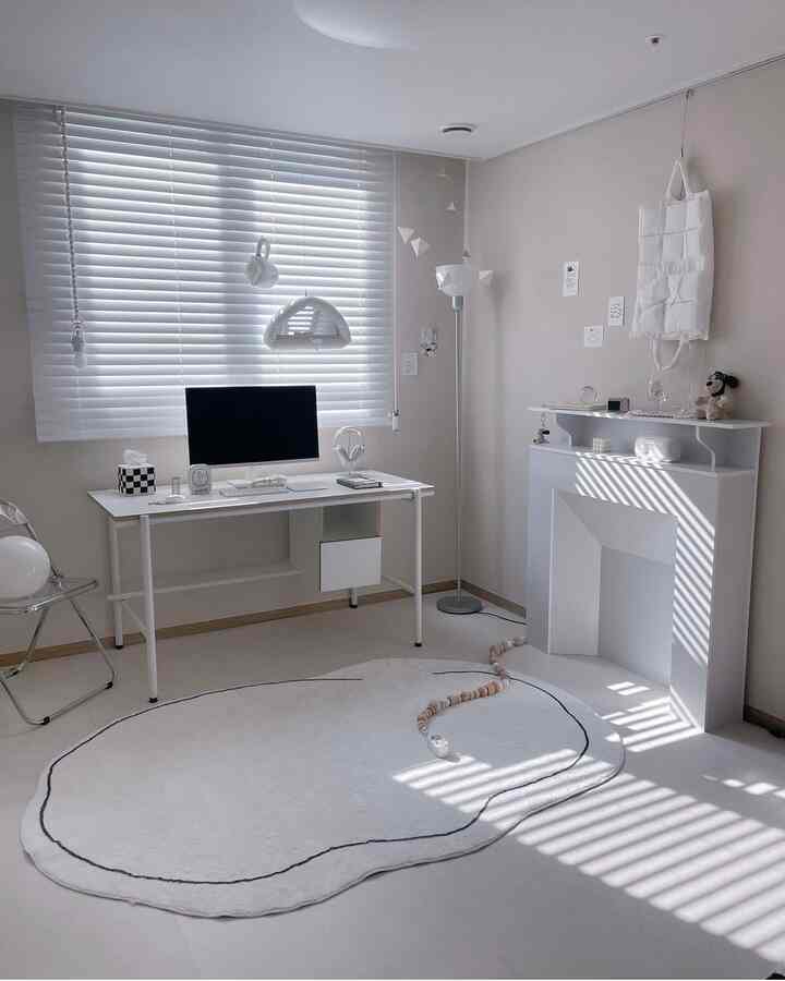 Modern and minimal studio apartment home office space in white tones with transparent chair and clean decor