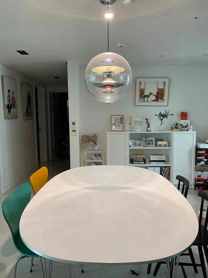 White-toned dining room featuring a Fritz Hansen dining table with colorful dining chairs, clean and modern atmosphere