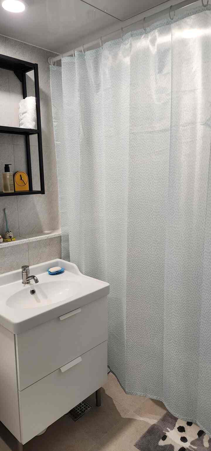 ホワイトトーンのバスルーム、イケアのシャワーカーテンと洗面台が配置されたシンプルで清潔感のあるインテリア