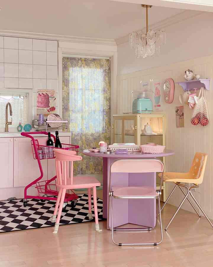 ピンクとラベンダーの色調が調和した可愛らしいキッチンとダイニングルーム、花柄のカーテンとヴィンテージの壁時計が印象的な空間
