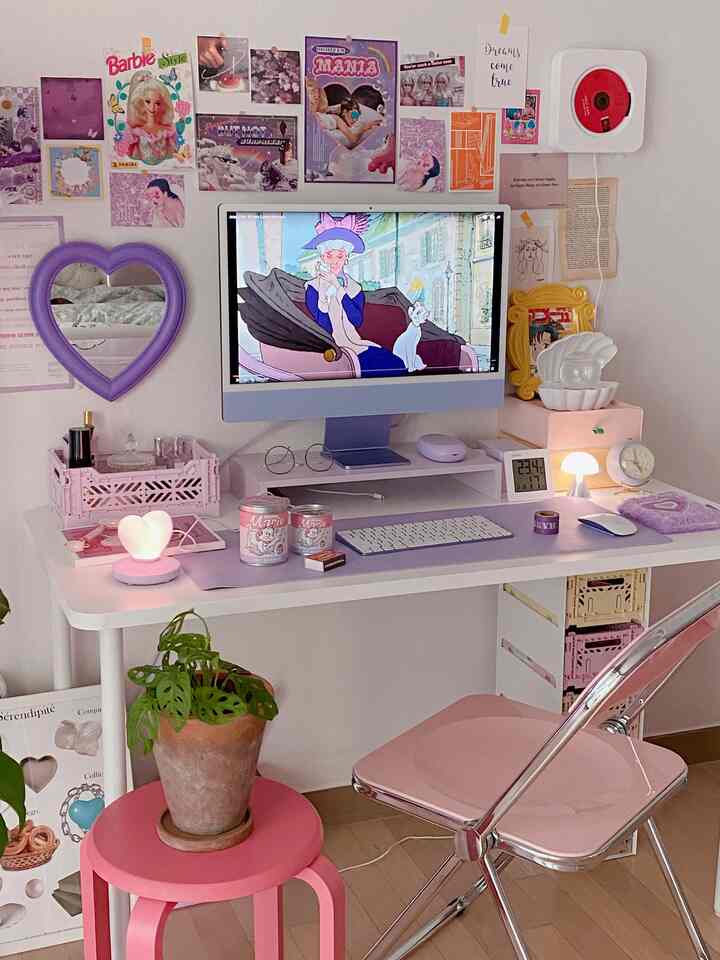Compact home office space in white and pink tones featuring a desk, chair, wall decor, and a plant on a pink stool