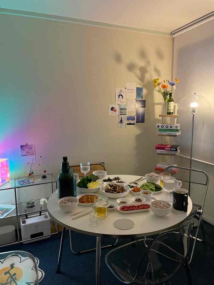 White and blue toned dining room featuring a clean round table set with diverse home party foods in a simple atmosphere