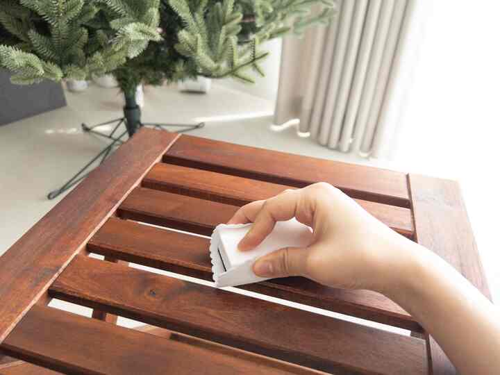 Bright and clean balcony space with a wood tone wooden stool being wiped by a hand holding a towel
