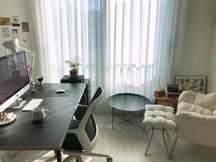 White and black toned home office living room featuring computer desk and comfortable armchair with simple design