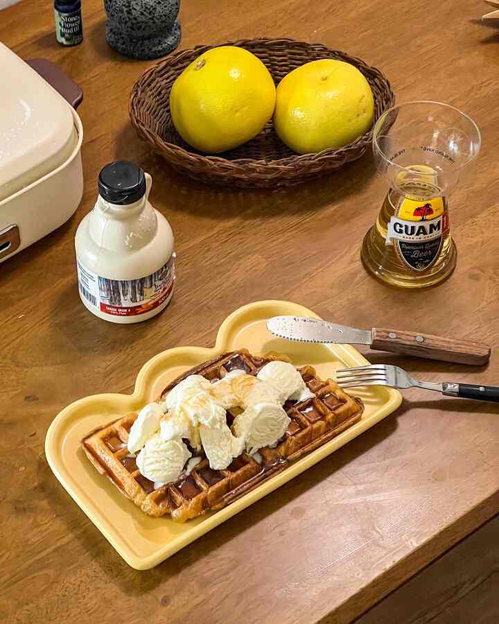 ナチュラルな木目調テーブルの上に黄色い皿とラタンバスケットが配置されたおうちカフェ風のデザート空間