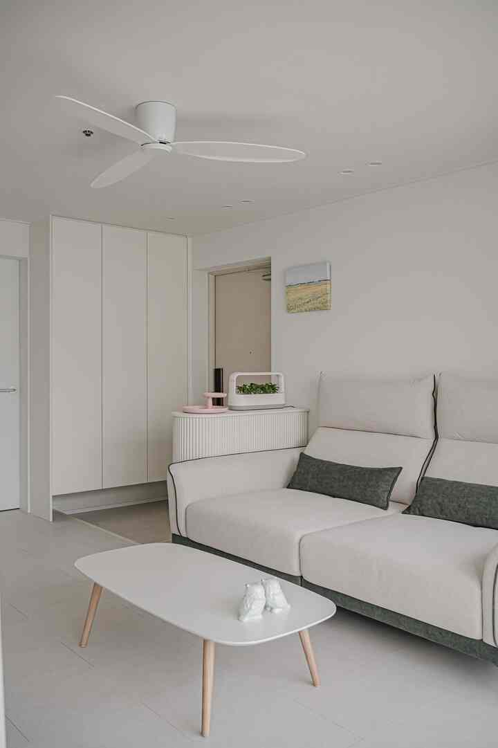 Bright white and wood tone living room featuring a sofa and coffee table in a simple modern setting