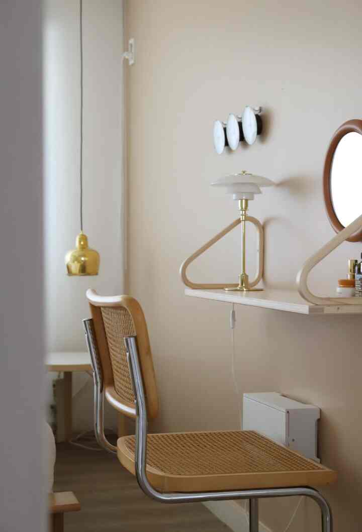 ナチュラルな木目調とゴールドの照明が調和するシンプルな寝室横のミニ化粧台スペース