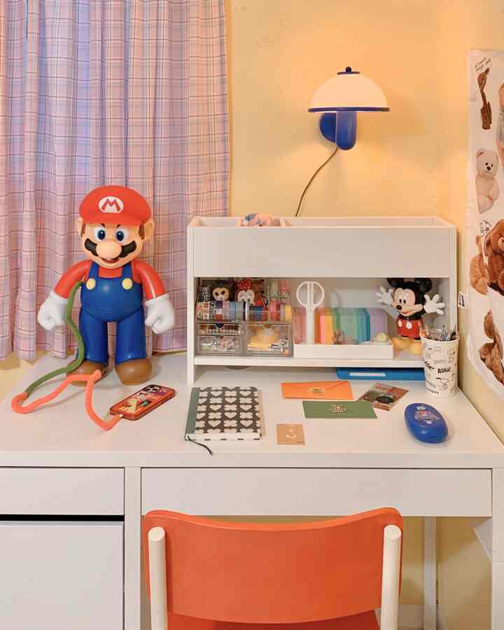 Bright and cozy kids' room desk space in white and orange tones, featuring toys and organized stationery accessories