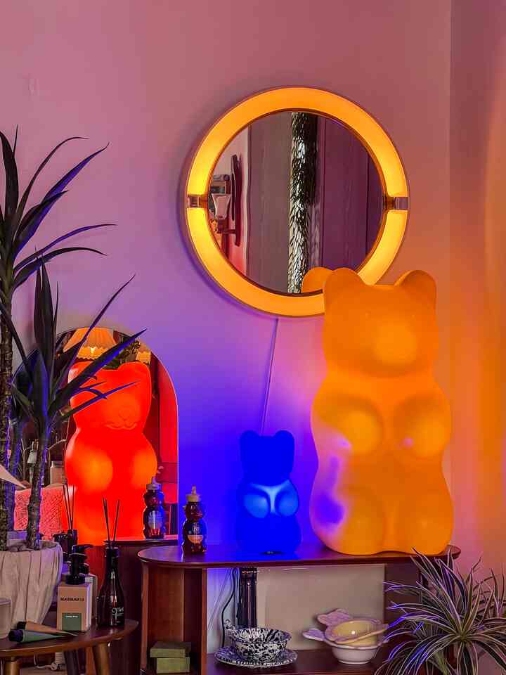 オレンジと紫の照明が印象的なナチュラルモダンな小さな部屋、クマ形のオブジェと植物が配置された温かみのあるインテリア