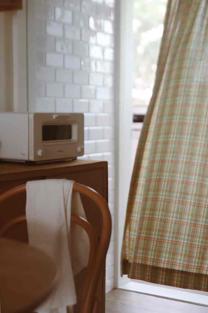 Yellow check curtain and brown wooden chair in a warm-toned kitchen space