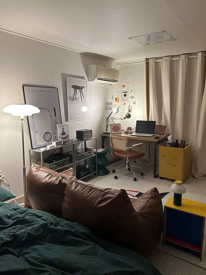 Ivory-toned studio apartment featuring a brown bean bag sofa and table lamps, creating a cozy home office interior