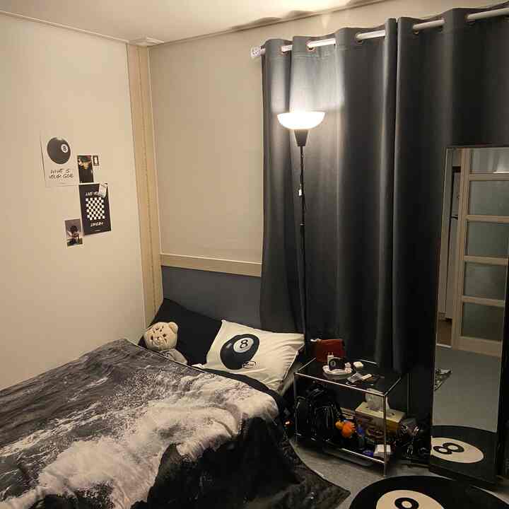 Black and white toned small bedroom featuring 8-ball motif bedding and blackout curtains creating a cozy atmosphere
