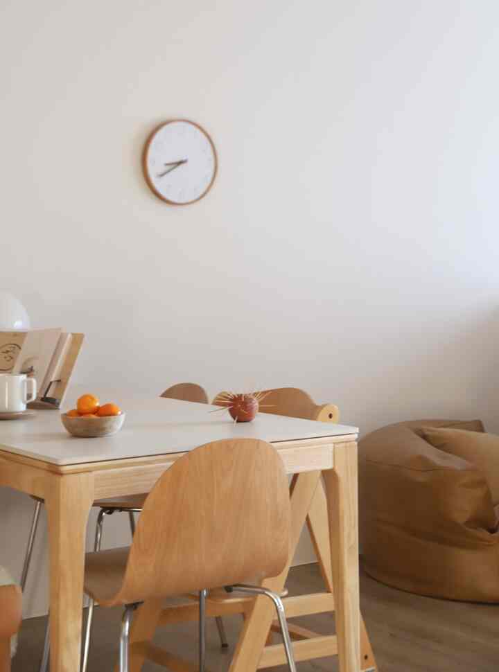 Natural wood and white tone dining room for four, with brown bean bag and minimalistic design