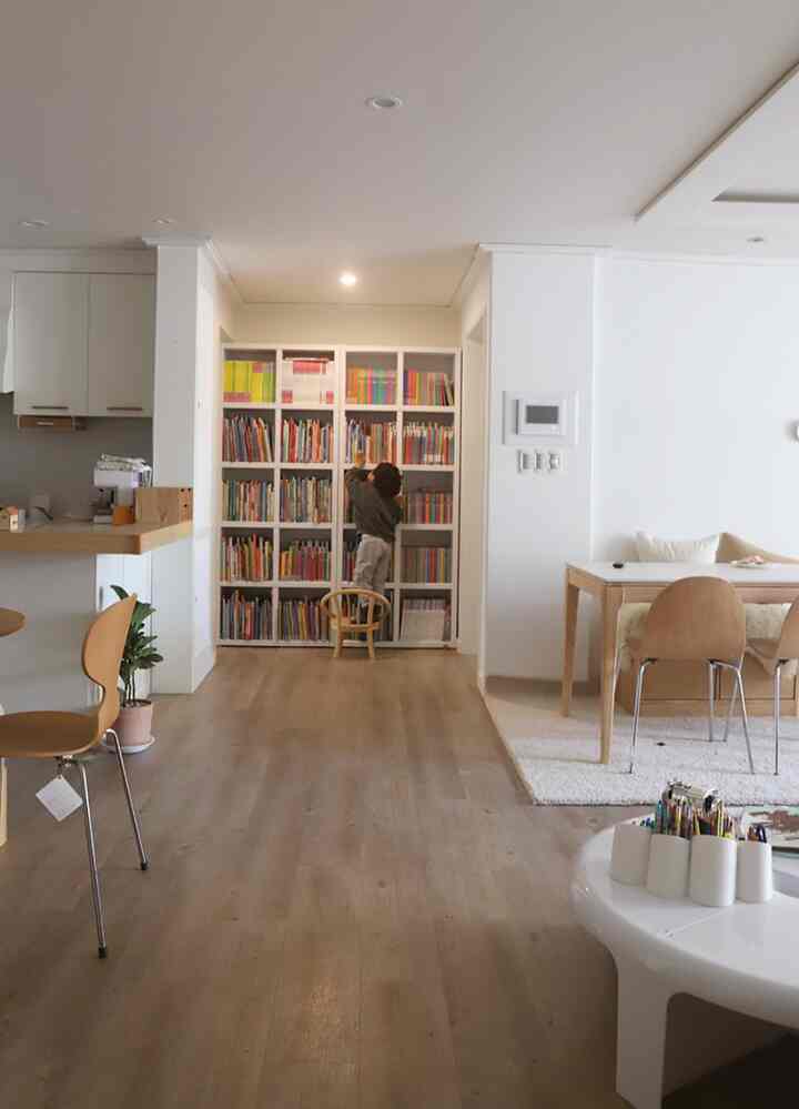 Natural tones and white walls in a living room featuring a front bookshelf with a child creating a cozy atmosphere
