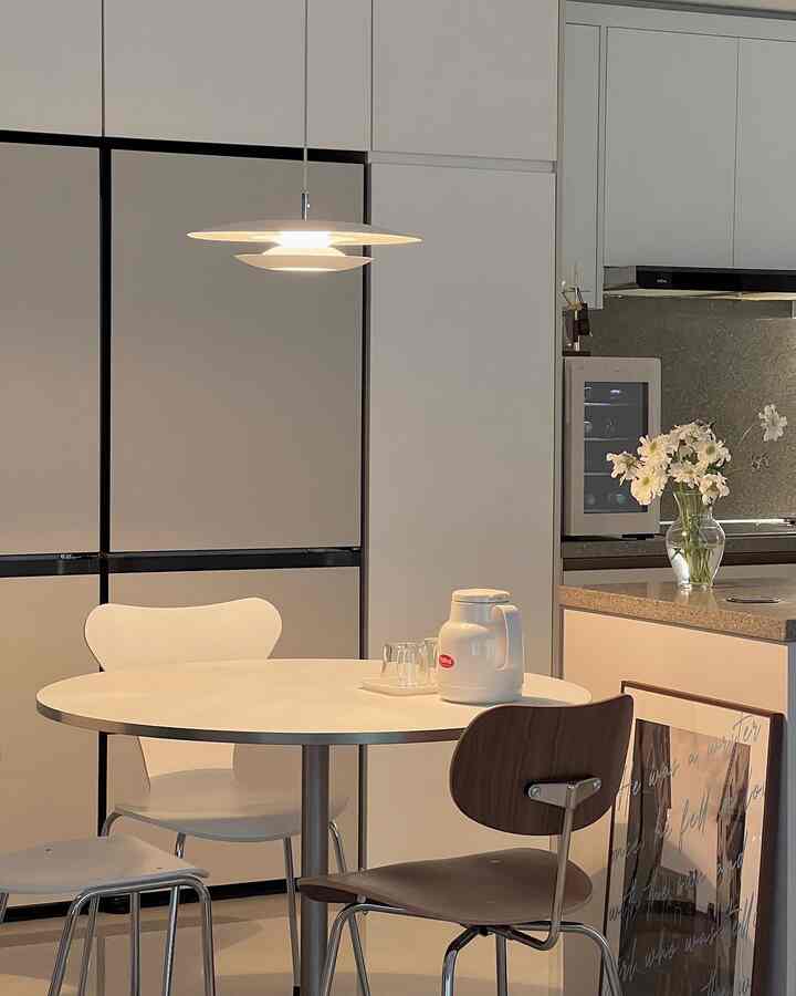 Modern kitchen space in white and brown tones featuring a round dining table and pendant light creating a balanced atmosphere