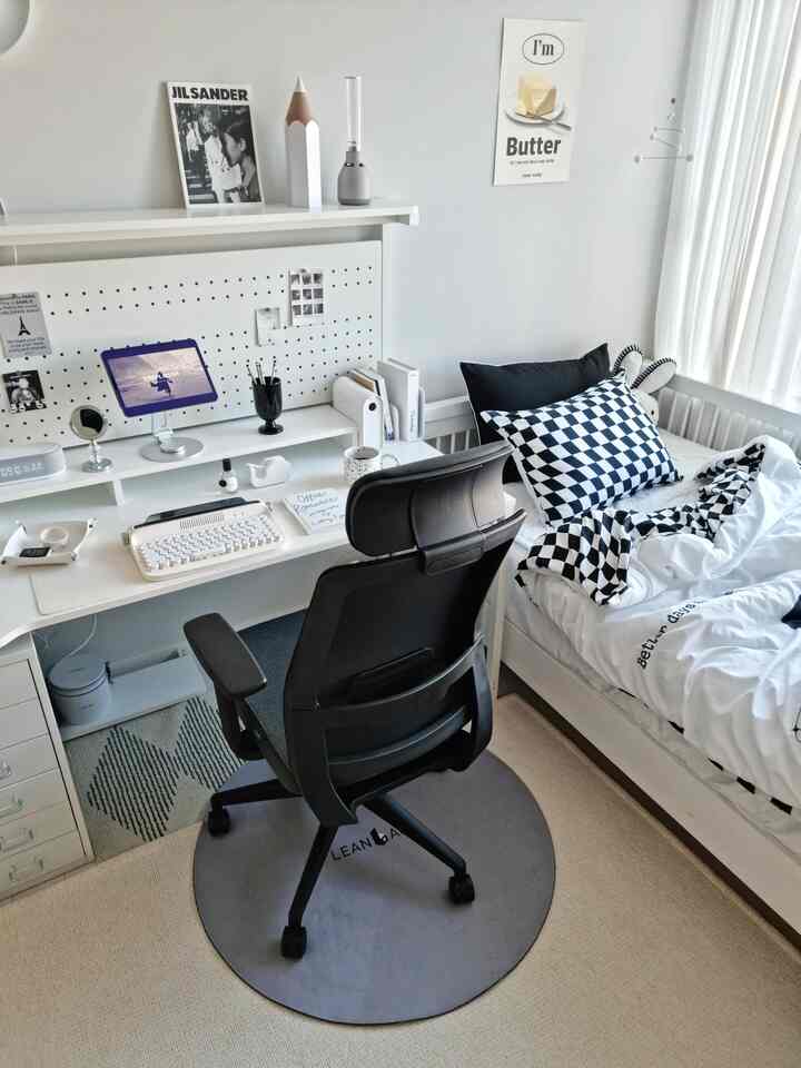 Modern black and white toned single household home office bedroom featuring desk, office chair, and bed in a clean layout