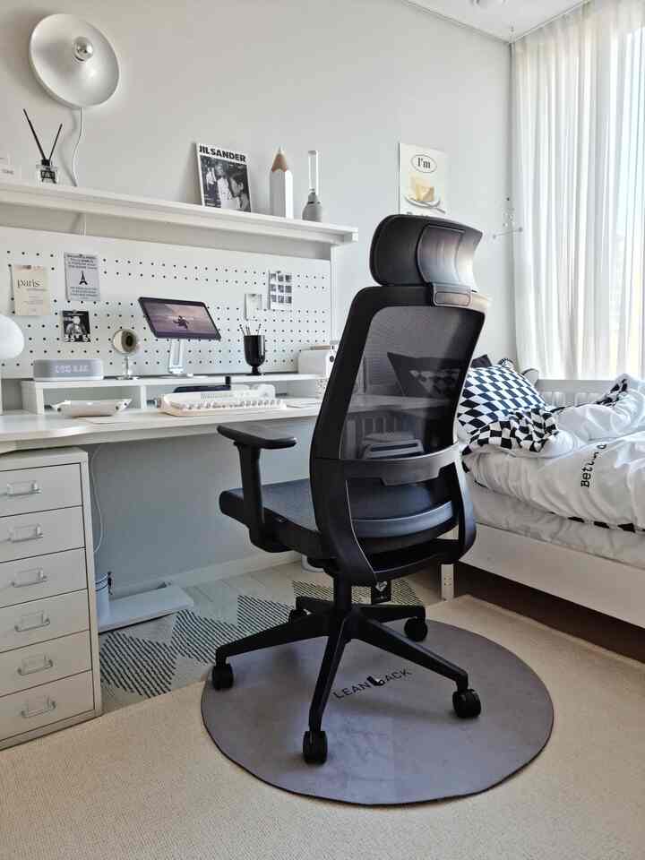 White and gray toned home office bedroom featuring ergonomic office chair and desk in a neat workspace