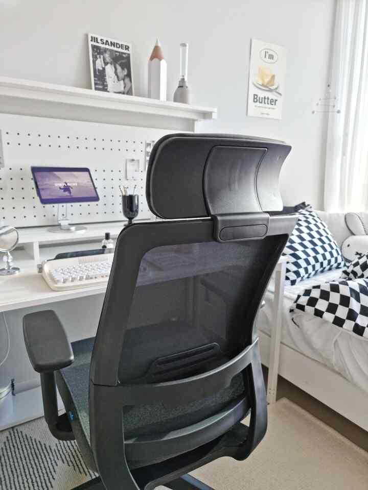 Modern bedroom in white and black tones featuring an office chair and desk suitable for remote work