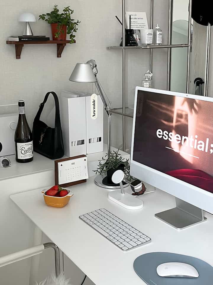 White and silver toned home office space featuring a desk with computer and desk lamp arranged neatly