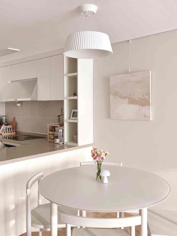 明るいホワイトトーンのキッチン、円形テーブルと椅子が配置されたナチュラルでモダンな雰囲気のインテリア