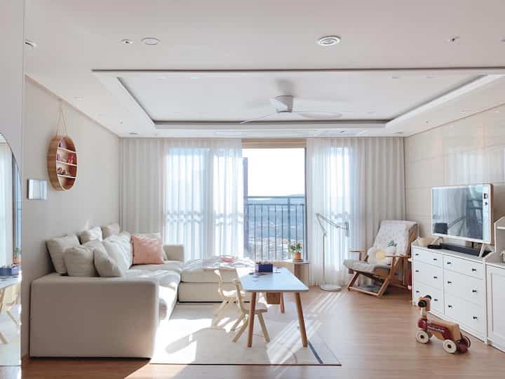 明るいホワイトと木目調のリビング、子供用家具とおもちゃが配置された温かみのある雰囲気のインテリア