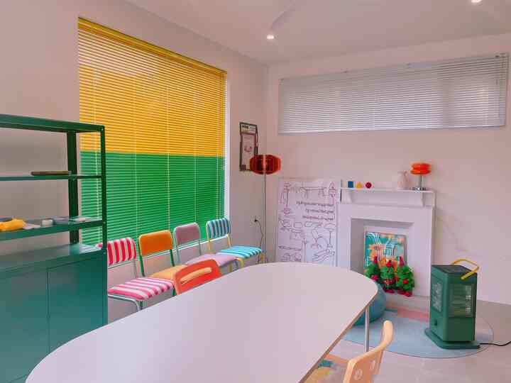 明るい黄色と緑のツートンブラインドがあるヴィンテージ風ダイニング、カラフルな円形テーブルと椅子が配置された空間