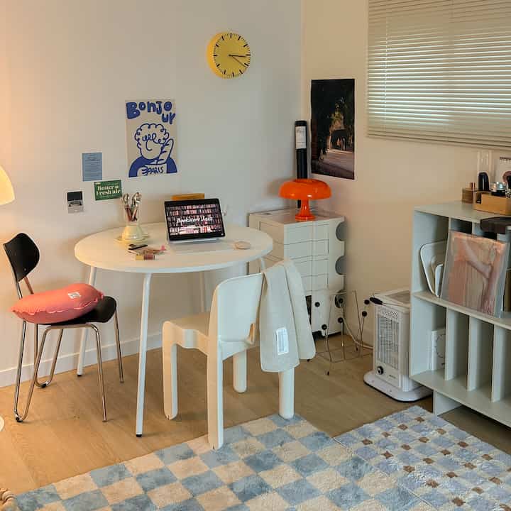 White and wood-toned compact workspace featuring a round table, B-line Bobby trolley, and mint rug in a cozy home cafe interior