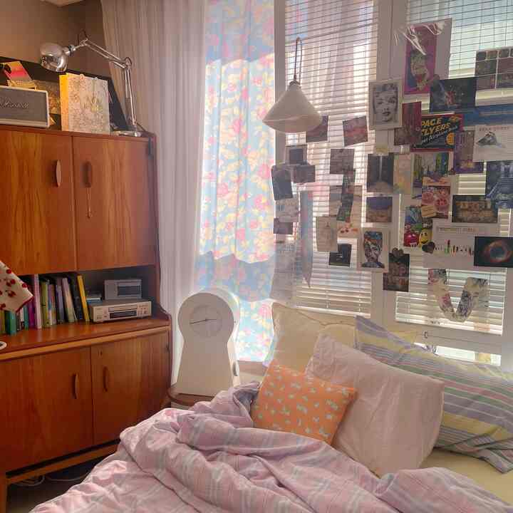 A cozy bedroom featuring warm wood tones and retro decor, with floral curtains and pastel bedding creating a soft atmosphere