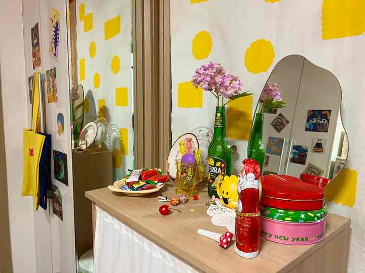 Cozy interior space featuring a table and an irregular shaped mirror against curtains with bright yellow and white patterns
