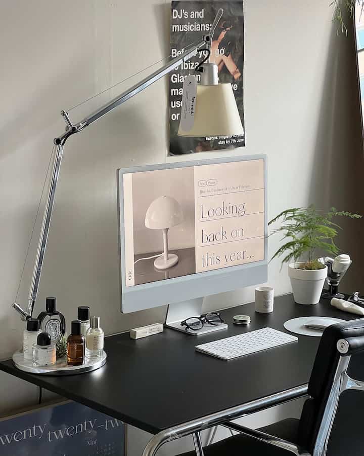 White-walled home office with black desk featuring mid-century modern elements and workspace essentials