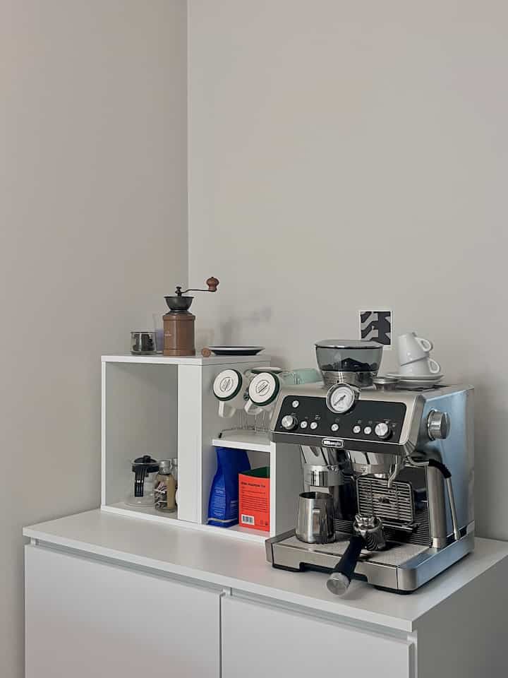 Modern white kitchen space featuring coffee machine and side table arranged in a compact home cafe setup