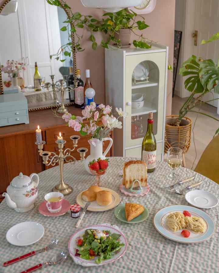 白と茶色のトーンが調和するダイニング、花瓶とワイングラスが置かれたテーブルと植物が配置された自然な雰囲気のインテリア