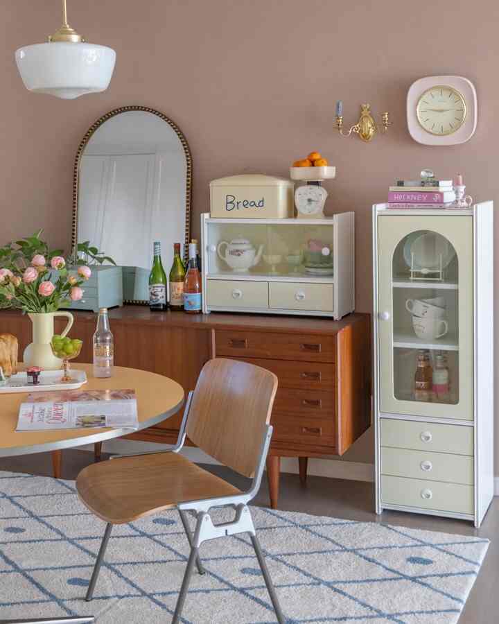 Dining room with soft beige-toned walls and wood-tone furniture, featuring wooden chair and patterned rug creating a warm atmosphere