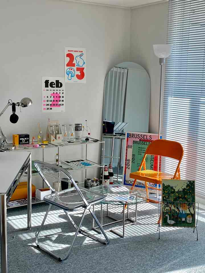 シルバーと透明感のある書斎、折りたたみ椅子とガラステーブルが配置された明るくミニマルな雰囲気のインテリア