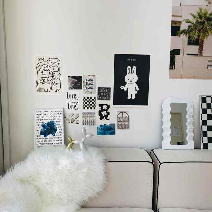 White and black toned living room featuring various posters, a fluffy white rug, and a unique mirror in a simple, natural setting