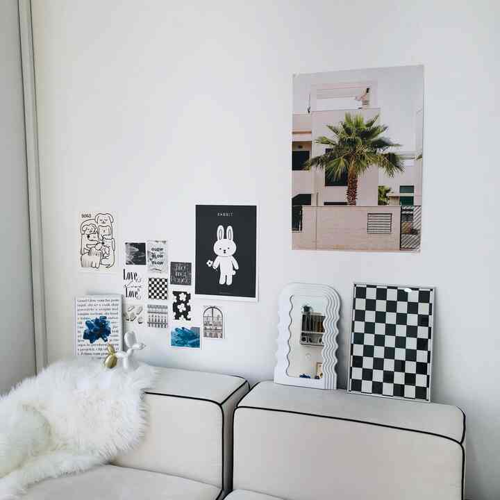 モノトーンのホワイトリビング、白いソファと壁に飾られた様々な額縁が配置された、清潔感のあるモダンなインテリア