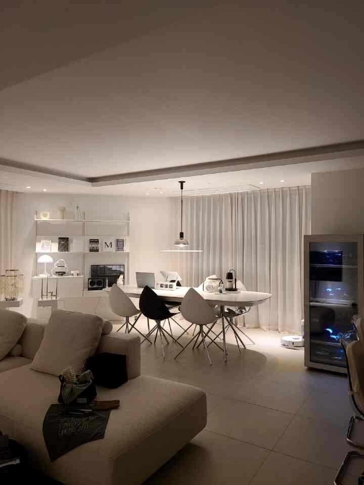 Beige-toned living and dining space featuring modern furniture and blackout curtains with cozy interior atmosphere