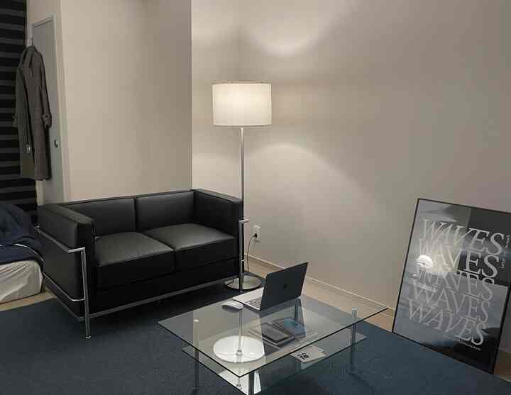 Black and white toned studio living room featuring glass table and modern furniture creating a neat home office space