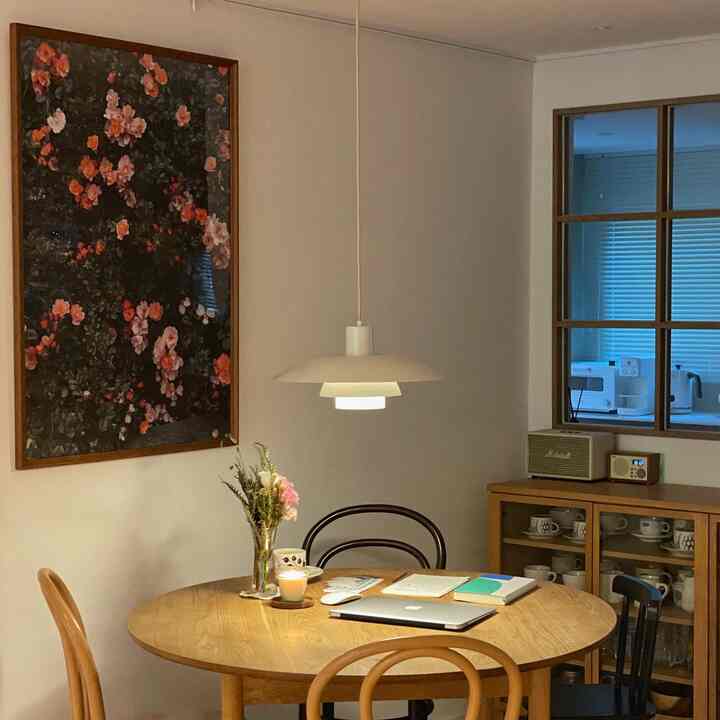 Wood tone dining room with white walls, featuring a pendant light above table and a floral poster, creating a cozy atmosphere