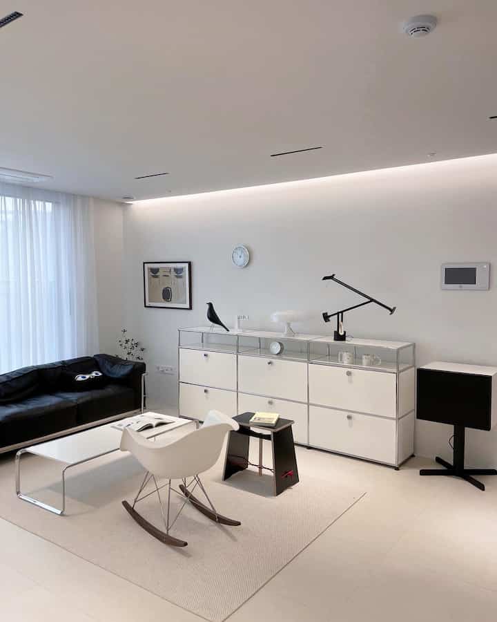Mid-Century Modern living room in white and black tones featuring rocking chair and simple furniture in a clean space