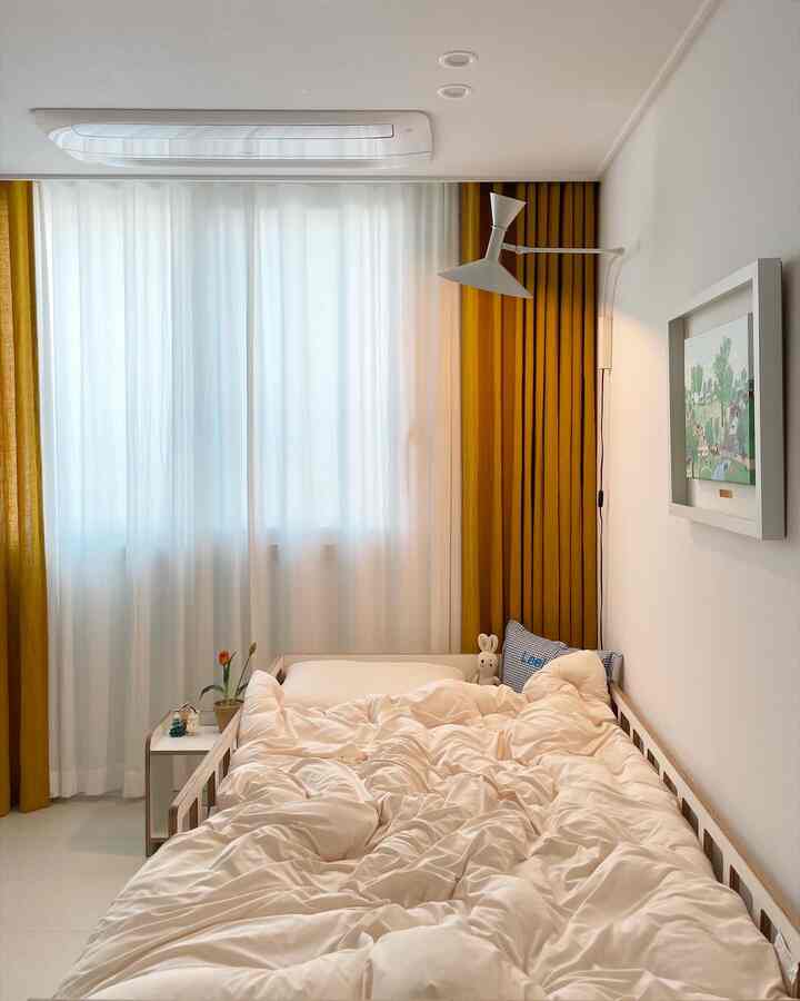 Bright and cozy kids' room featuring wood tone bed and mustard curtains