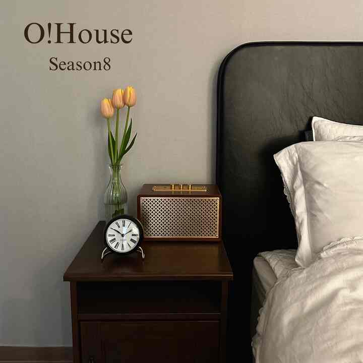 Cozy bedroom featuring brown wood tone nightstand, black leather bed head, and white bedding with soft atmosphere
