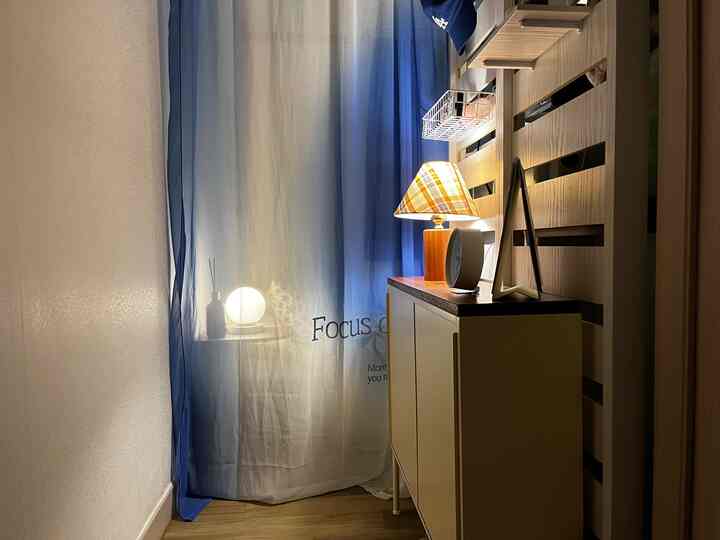 Wood tone dressing corner with warm lighting and room divider in a compact walk-in closet space