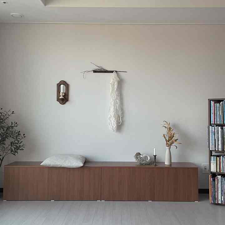 ナチュラルなブラウン調のリビング、ウォールナットの収納家具とヴィンテージ雑貨、壁掛け鏡と燭台が配置されたシンプルで落ち着いたインテリア