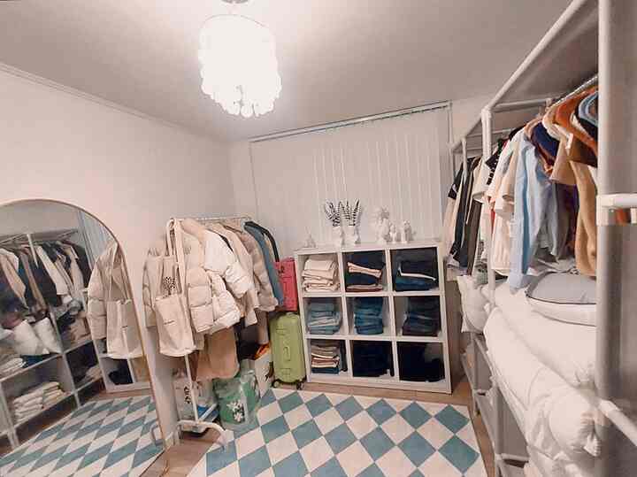 白と青のトーンのウォークインクローゼット、アーチ型の全身鏡と服掛けが配置された印象的な空間