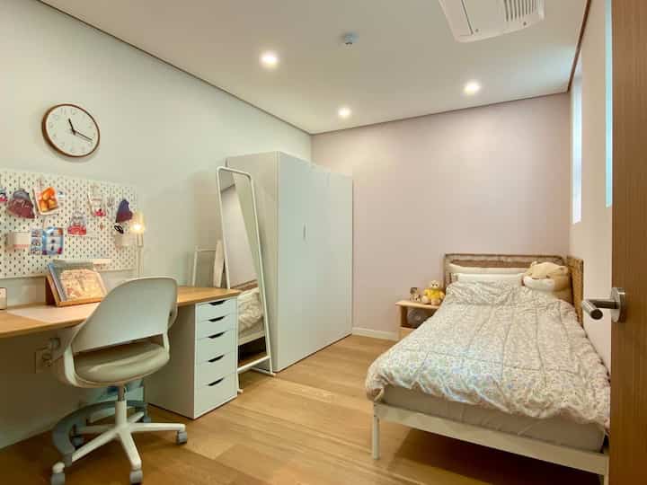 白と木目調の子供部屋、ベッドとデスクが配置された落ち着いた雰囲気の空間