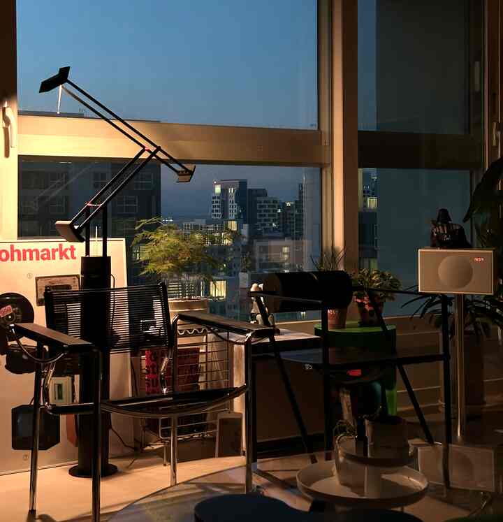 Earth tone living room featuring central black armchairs and lighting, with cozy interior and city night view through window