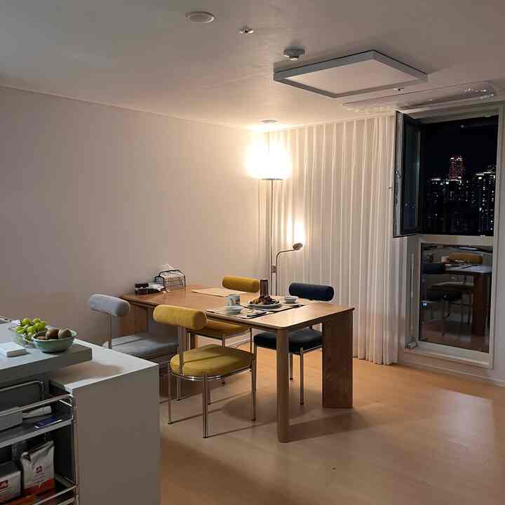 Dining room with white walls and wood tone floor, colorful dining chairs and warm lighting create a cozy atmosphere